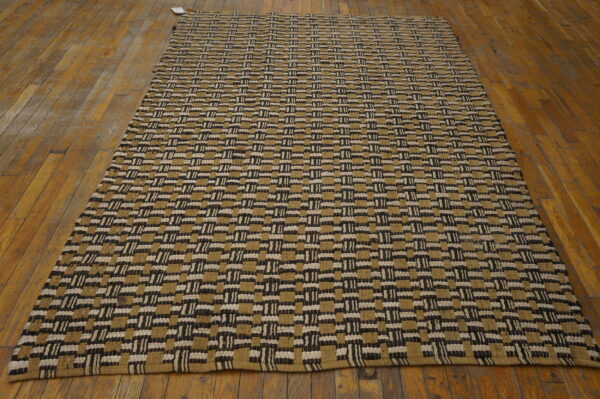 Flatweave rug featuring thick black, cream, and khaki rectangular geometric blocks on wood flooring.