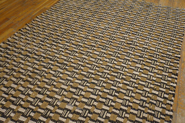 Woven rug featuring alternating blocks and dashes in tan, cream, and dark brown on hardwood flooring.