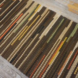 Textured striped runner in browns, beige, and accent colors lies on gray distressed wood floor.