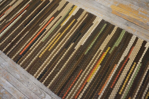 Textured striped runner in browns, beige, and accent colors lies on gray distressed wood floor.