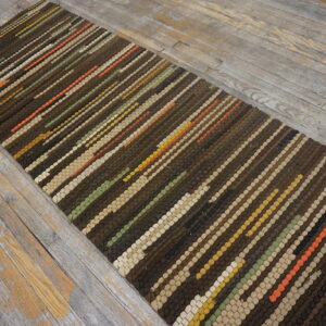 Brown, beige, and multicolored diagonal striped runner on a worn gray wood floor.