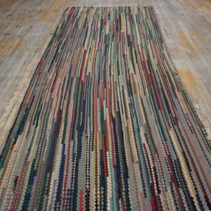 Multicolor, textured runner rug with vertical strips of various colors laid on gray and yellow wooden planks.