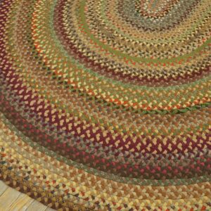 A round braided rug in concentric rings of brown, green, and maroon rests on light wood flooring.