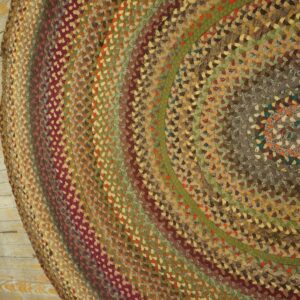 Braided rug featuring concentric bands of mixed maroon, brown, green, and tan fabric on wood flooring.