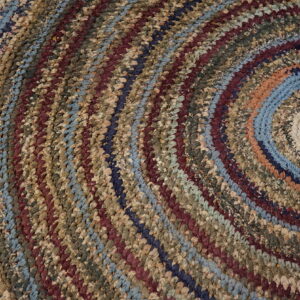 Close-up of a chunky braided rug forming concentric circles in diverse earth tones, blues, and maroon.