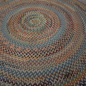 Close-up view of a braided round rug with multicolored concentric rings on rustic wood planks.