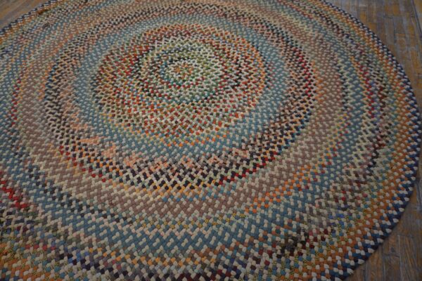 Close-up view of a braided round rug with multicolored concentric rings on rustic wood planks.