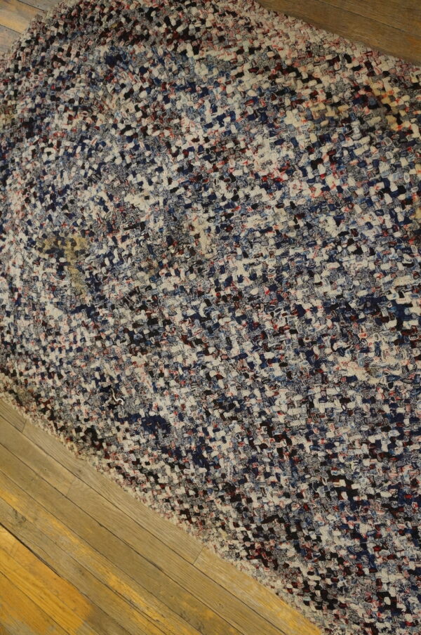 Heavily textured woven rug with multicolored blocks of white, blue, red, and black on wood planks.