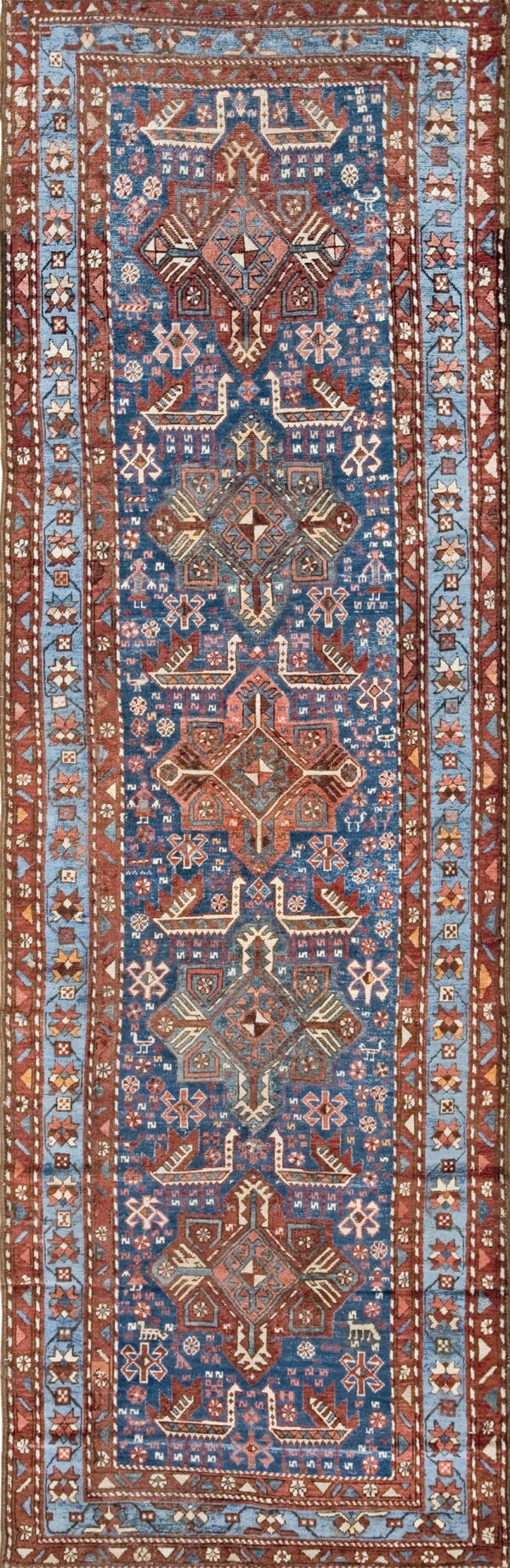 Deep blue runner rug with complex geometric patterns in terracotta, powder blue, and cream.