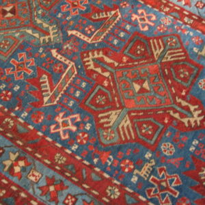 Geometric rug detail showing a pattern of large red, blue, and tan tribal medallions.