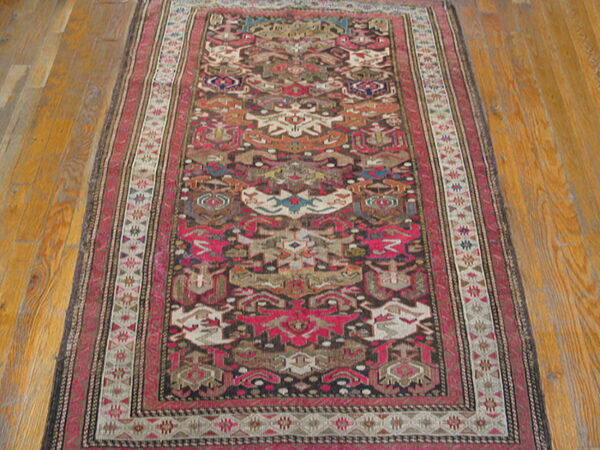 Geometric runner rug with deep red, black, teal, and beige tribal patterns on polished hardwood.