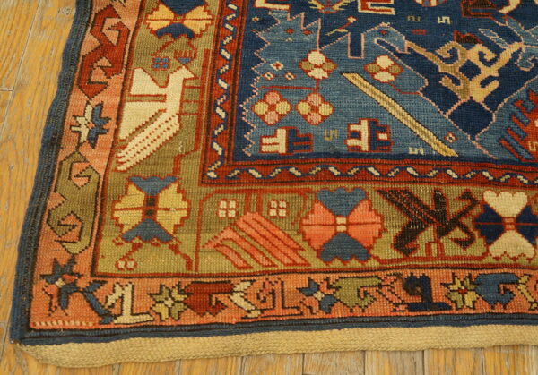 Geometric blue, terracotta, and olive green rug corner featuring a stylized bird pattern on a wood floor.