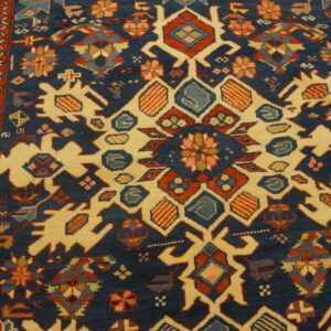 Geometric rug detail showing large cream motifs against a navy field with red, rust, and blue accents.