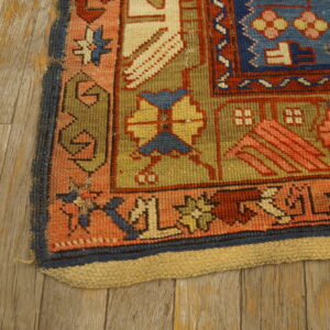 Detail of a tribal geometric rug featuring blue, red, and olive green on distressed wood flooring.
