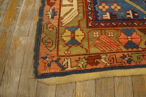 Detail of a tribal geometric rug featuring blue, red, and olive green on distressed wood flooring.