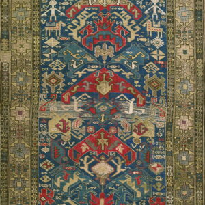 Detailed geometric rug in blue, red, beige, and olive green features stylized figures and animals.