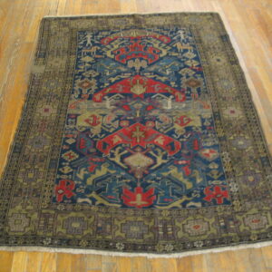 Geometric rug in blue, red, and khaki on shiny light brown hardwood flooring.