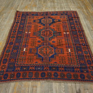 A rust and navy geometric patterned rug with a deep field lies on rustic wooden floorboards.