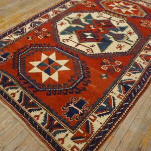 Low-pile rug in rust red, navy blue, and cream geometric patterns on distressed wood planks.