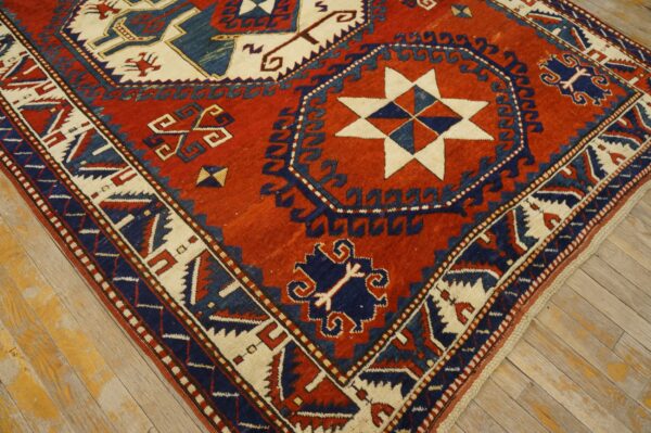 Geometric rug in deep red, navy, and cream with star and medallion motifs on distressed wood flooring.