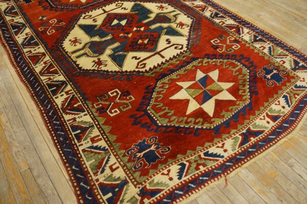 A geometric rug in red, navy, cream, and green sits on distressed wood flooring.