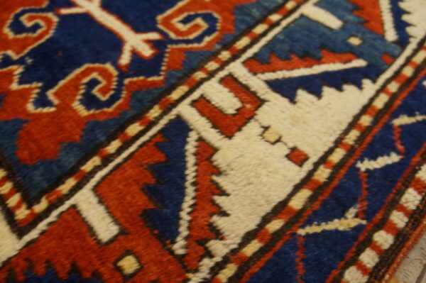 Dense pile rug detail showing geometric patterns in blue, rust red, and cream colors.