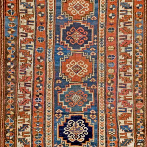 Low-pile rug with central geometric medallions and multiple borders in blue, rust, and cream.
