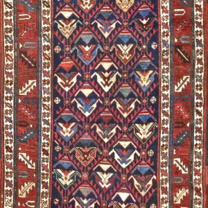 Dark blue rug with stylized geometric motifs and multiple red borders featuring tribal elements.