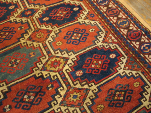 Red and navy geometric rug with cream outlining and complex medallions visible on wood flooring.