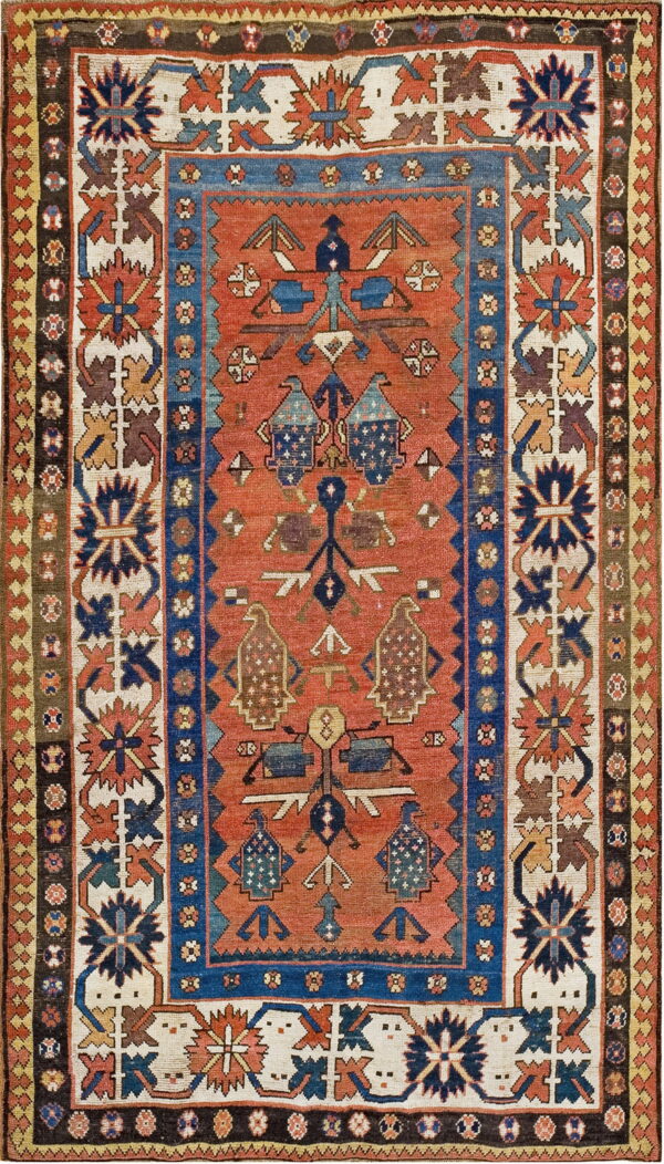 Geometric rug with stylized motifs on a burnt orange field, framed by complex blue and cream borders.