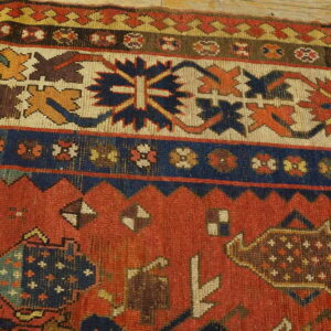 Geometric red, navy, and cream rug detail showing tribal motifs near light wooden flooring.