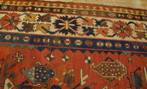 Geometric red, navy, and cream rug detail showing tribal motifs near light wooden flooring.