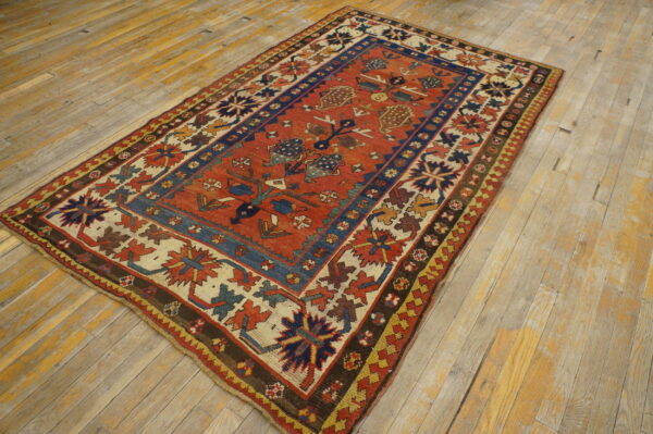 A tribal-patterned rug featuring rust red, navy blue, and cream sits on distressed wood planks.