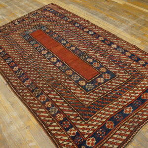 Rust and navy geometric rug with a solid central field displayed on rustic wood flooring.