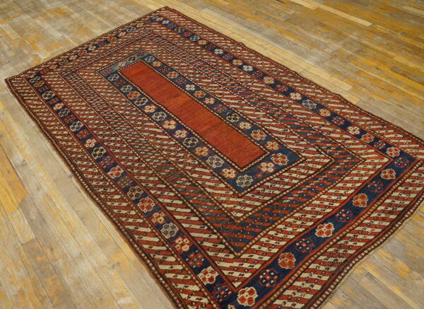 Rust and navy geometric rug with a solid central field displayed on rustic wood flooring.
