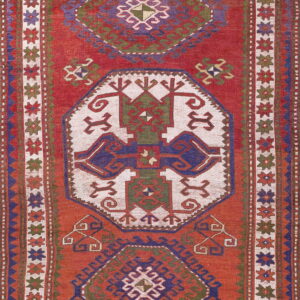 Rust red flat weave rug featuring geometric medallions rendered in cream, blue, and olive green.