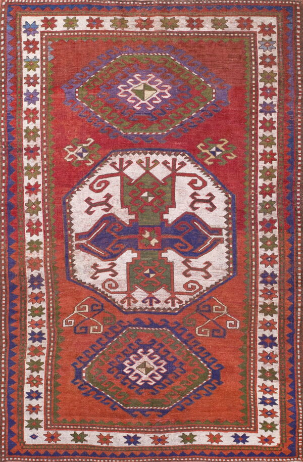 Rust red flat weave rug featuring geometric medallions rendered in cream, blue, and olive green.