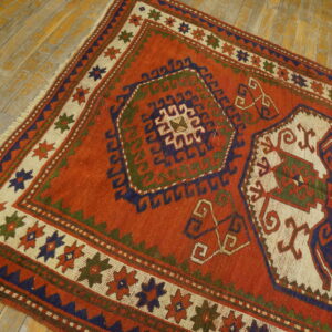 Low-pile rust rug featuring geometric designs in navy, olive, and cream on distressed wood flooring.