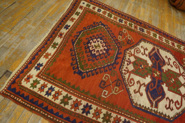Low-pile rust rug featuring geometric designs in navy, olive, and cream on distressed wood flooring.
