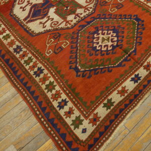 Low-pile geometric rug in orange, navy, and cream bordered by stars on worn plank flooring.