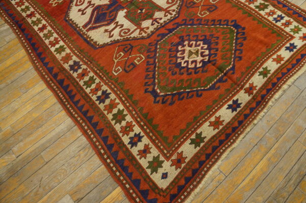 Low-pile geometric rug in orange, navy, and cream bordered by stars on worn plank flooring.