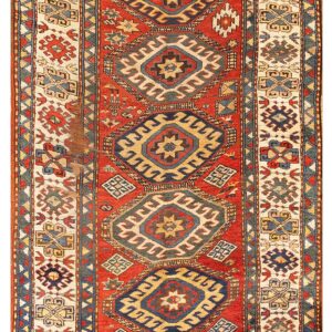 Low-pile red runner rug featuring stacked geometric medallions in blue, cream, gold, and visible patina.