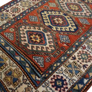 Geometric rug featuring a deep red field, navy medallions, and a wide ivory border.