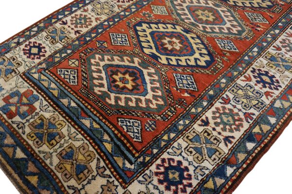 Geometric rug featuring a deep red field, navy medallions, and a wide ivory border.