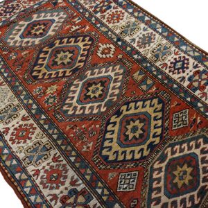 Runner rug featuring a large geometric design of diamonds in deep red, navy, and cream.