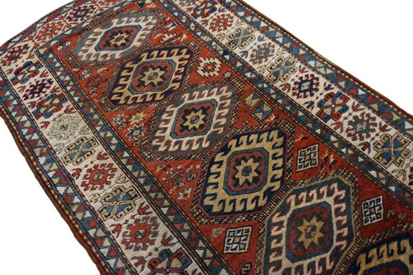 Runner rug featuring a large geometric design of diamonds in deep red, navy, and cream.