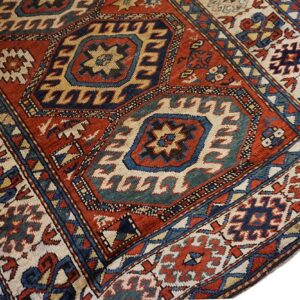 Red, navy, and cream geometric rug detail showing large central medallions and complex borders.