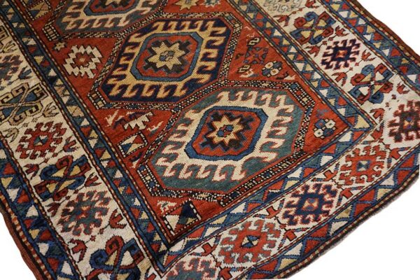 Red, navy, and cream geometric rug detail showing large central medallions and complex borders.