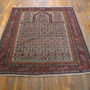 Red and blue geometric rug featuring a detailed lattice pattern over a cream field on warm wood flooring.