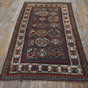 Red, blue, and cream tribal rug with geometric designs laid across distressed wood flooring.
